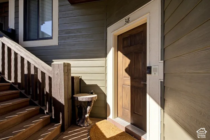 Wood-paneled entry door with white trim, wood siding, and exterior stairs with a wood railing