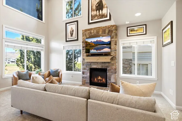 Vaulted ceiling with multiple windows, stone-clad fireplace, and a wood mantel