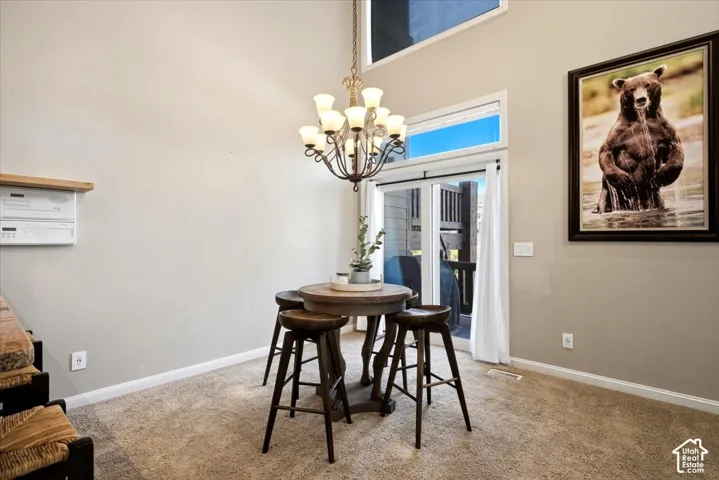Vaulted ceiling dining area featuring a wrought iron chandelier, recessed lighting, and carpeted flooring
