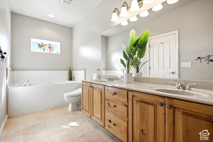 Integrated soaking tub with chrome fixtures, dual vanity with wood cabinetry, light-colored countertops, tile flooring, and a large mirror with overhead lighting