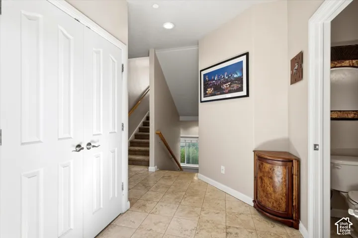 Entryway featuring tile flooring, a carpeted staircase with wood handrails, and a nearby half-bathroom
