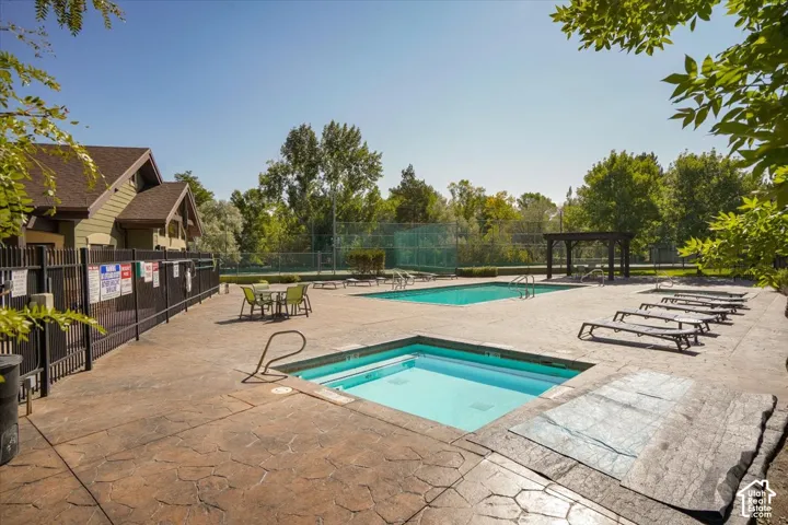 Resort-style amenities featuring a rectangular swimming pool, integrated spa, and an adjacent shaded pergola