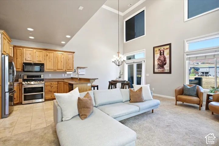 Open-concept living area with vaulted ceilings, natural wood cabinetry, stainless steel appliances, and abundant natural light from multiple windows
