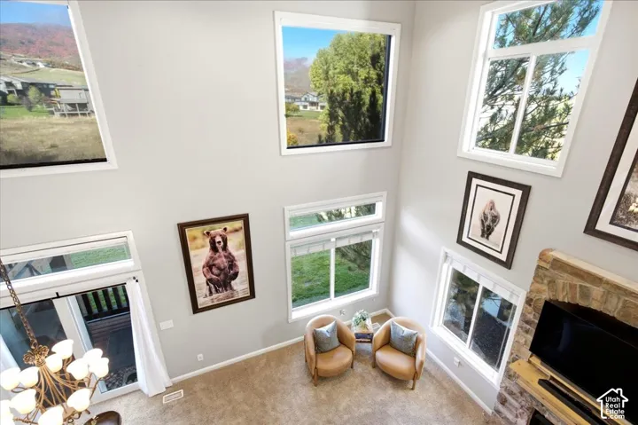 Double-height ceilings with high-level windows, stone-clad fireplace, and neutral wall tones