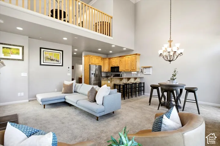 Vaulted ceiling with a wood-railed loft overhead, recessed lighting, and a kitchen featuring wood cabinetry, stainless steel appliances, and a breakfast bar