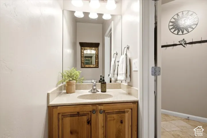 Wood-finish vanity with a built-in sink, neutral countertop, and large wall-mounted mirror
