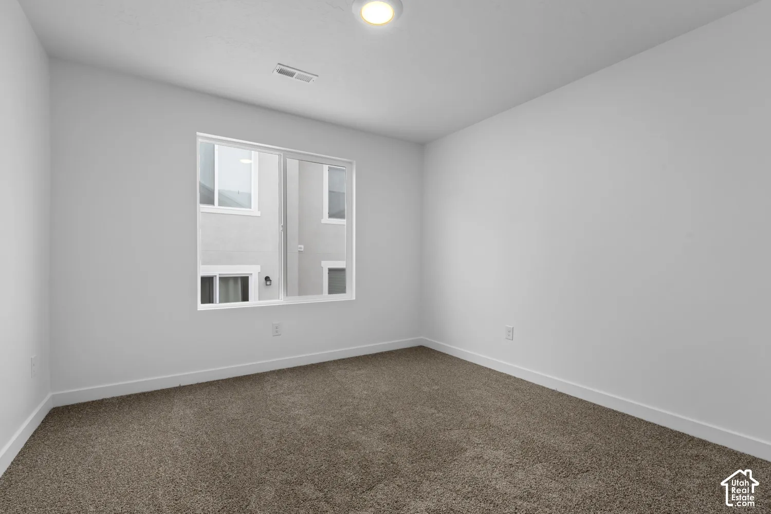 Textured carpeting, white walls, recessed ceiling light, and a white-framed window
