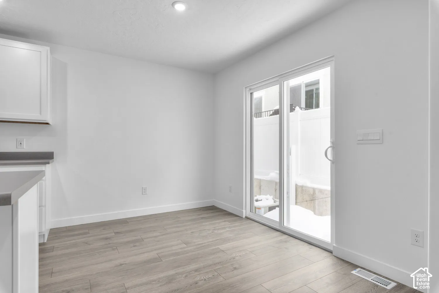 White cabinetry with gray countertops, wood-finish flooring, and a sliding glass door