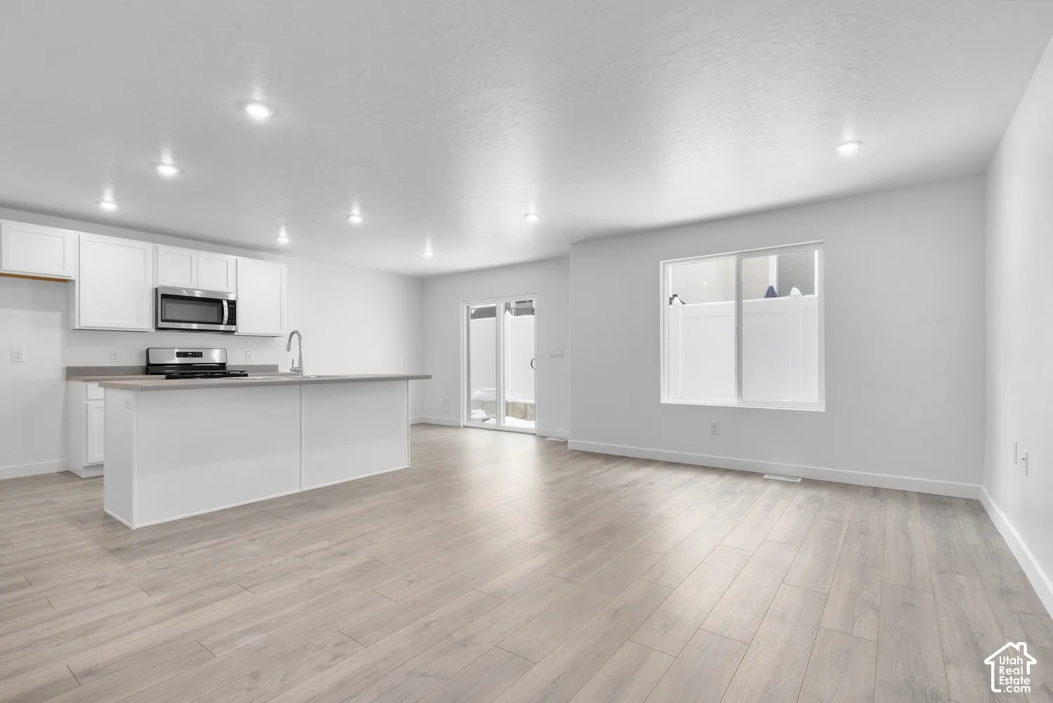 Recessed lighting illuminating the open-concept space featuring wood-finish flooring
