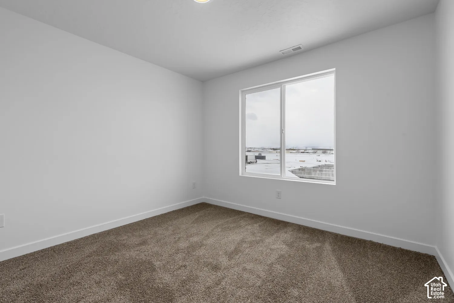 Recessed ceiling lighting, white walls, large window, brown carpet, and white trim