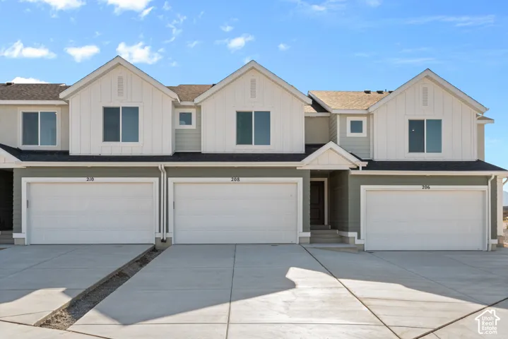Multi-unit exterior featuring vertical board-and-batten siding, horizontal lap siding, multi-gabled rooflines, and attached two-car garages with concrete driveways
