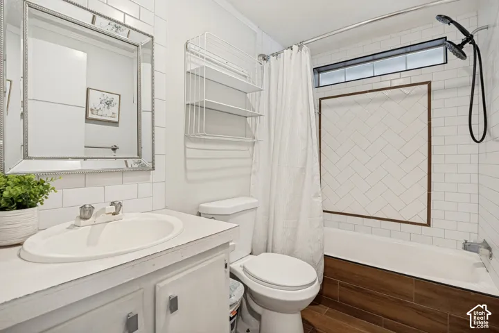 Bright, updated bathroom showcasing crisp white subway tile walls, a framed mirror with chrome hardware, a pedestal sink with chrome fixtures, and a walk-in shower enclosure with glass door and wood-finish surround