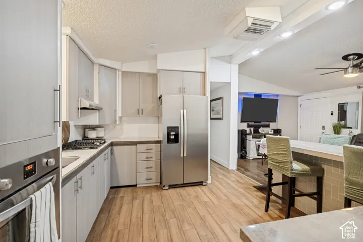 Modern kitchen featuring stainless steel appliances, light wood-finish cabinetry, a gas cooktop, and wood-finish flooring