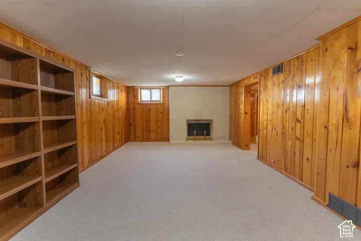 Wood-paneled room featuring built-in shelving, a brick fireplace, and wall-mounted light fixtures