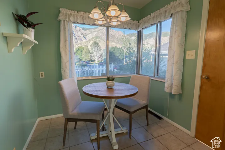 Bay window with mountain scenery, overhead chandelier, and tile flooring