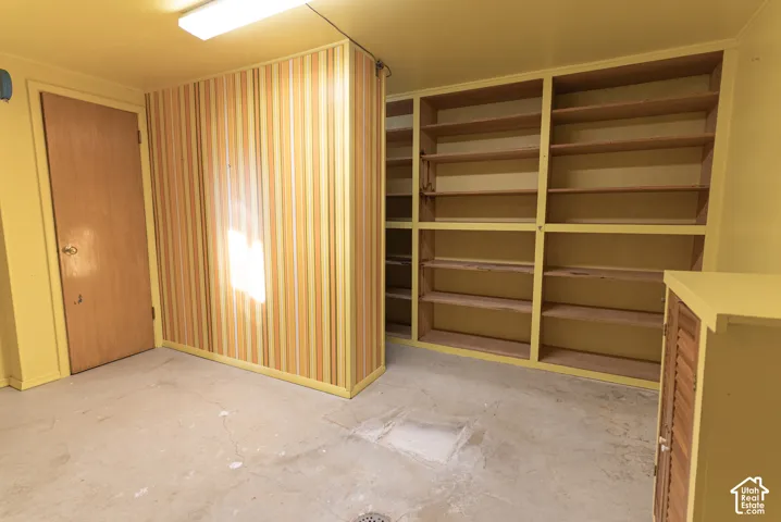 Built-in open shelving, concrete flooring, and a flush-mount overhead light fixture