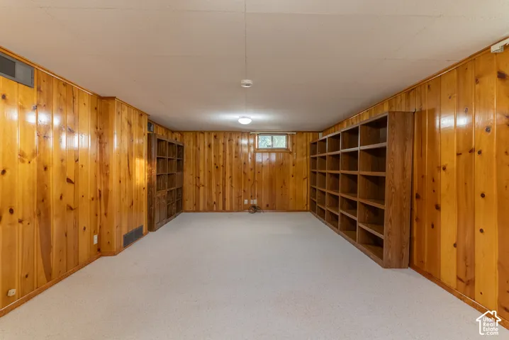 Recessed lighting, light-toned carpeting, wood paneling, and built-in shelving units