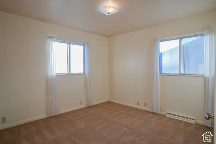 Neutral tone wall paint, carpet flooring, and ceiling-mounted light fixture