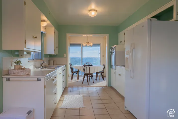 Galley kitchen featuring white cabinetry, stainless steel appliances, ceramic tile flooring, and mint-green accent walls