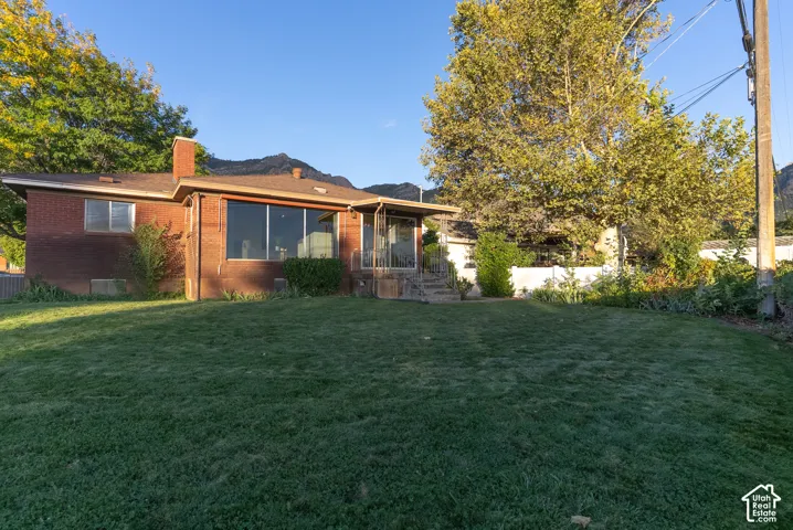 Expansive grassy yard with mature trees, a brick exterior, and a large window wall