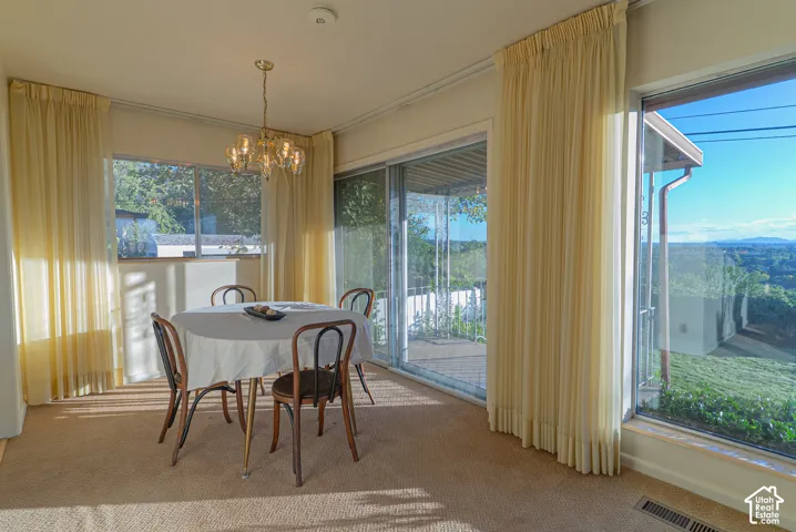 Wall-to-wall carpeting and a brass-toned chandelier illuminate this dining area