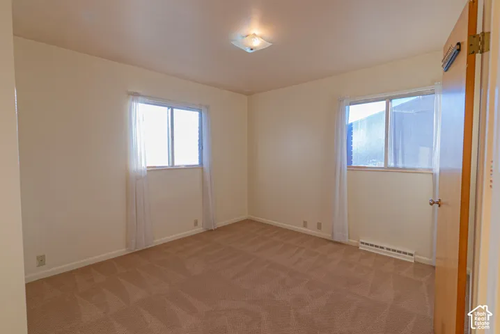 Room featuring light-toned carpeting, two windows, and neutral wall paint
