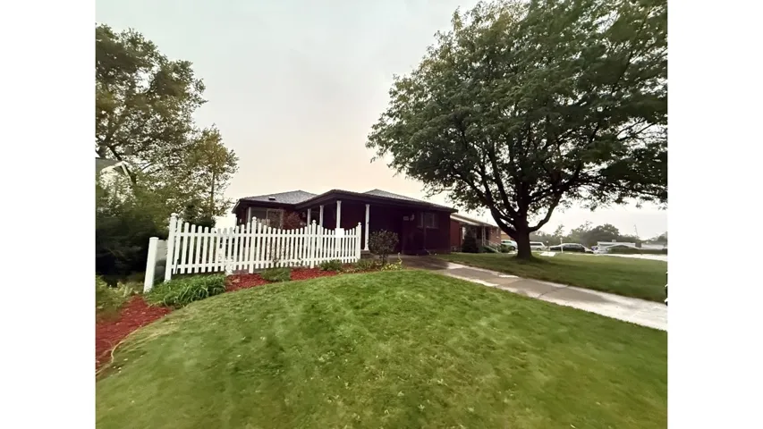 Gabled roofline, covered front porch, white picket fence, landscaped front yard, mature tree