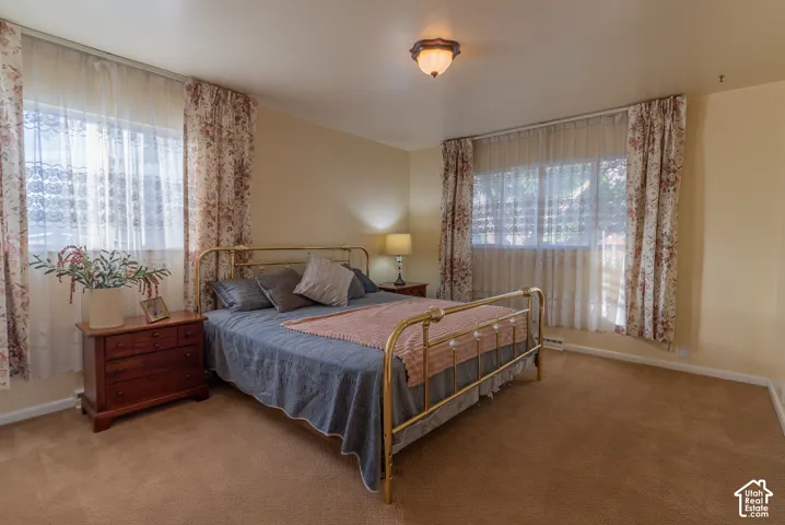 Dual windows with sheer and floral drapes, providing natural illumination