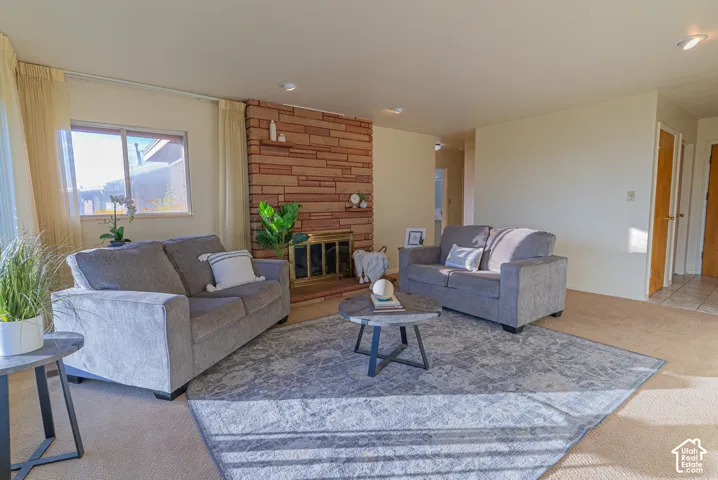 Living area featuring a brick fireplace, built-in fireplace screen, and neutral-toned carpeting