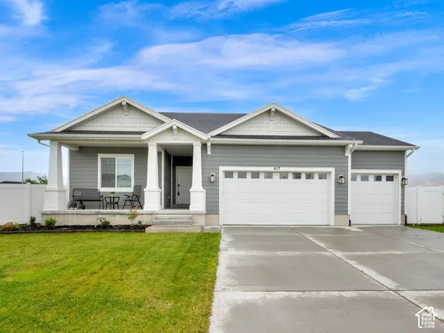 Single-story exterior with gray siding, a covered front porch, & a three-car garage.