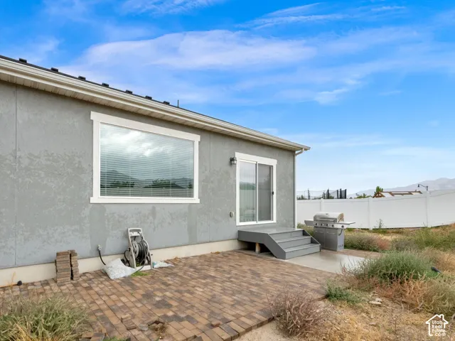 Rear exterior featuring a sliding glass door and a brick paver patio