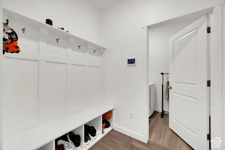 Built-in hall tree with storage cubbies and coat hooks, wood-finish flooring, white trim, and a white interior door
