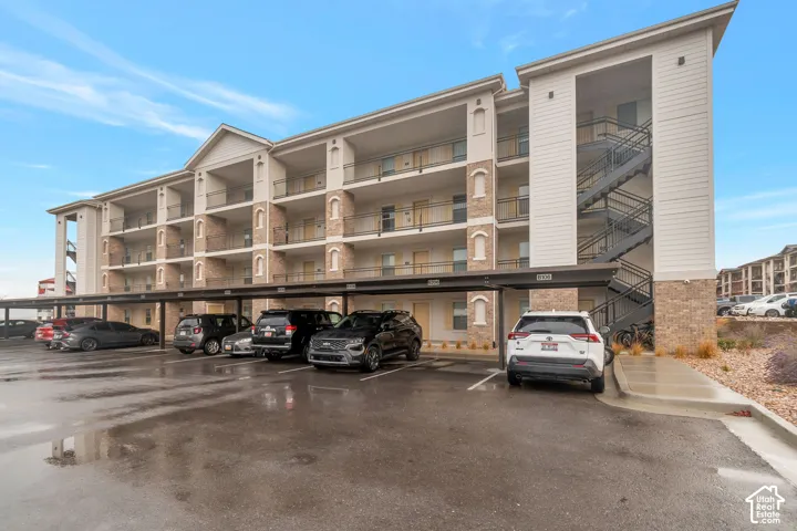Multi-story building featuring brick-finish facade accents, individual balconies with metal railings, exterior stair access, and covered parking