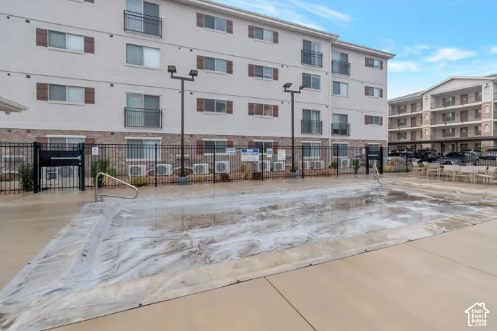 Outdoor pool area with a covered pool, adjacent patio space, and wrought iron fencing