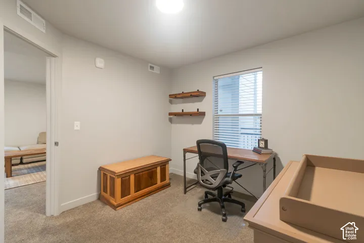 Recessed lighting, light gray wall paint, window with blinds, wall-mounted wooden shelves, and carpeted flooring