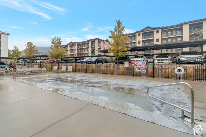 Outdoor pool area with a covered pool, concrete decking, and metal handrails