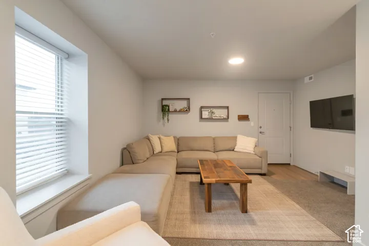 Recessed ceiling lighting, light gray wall tones, wood-finish flooring, and a window with blinds