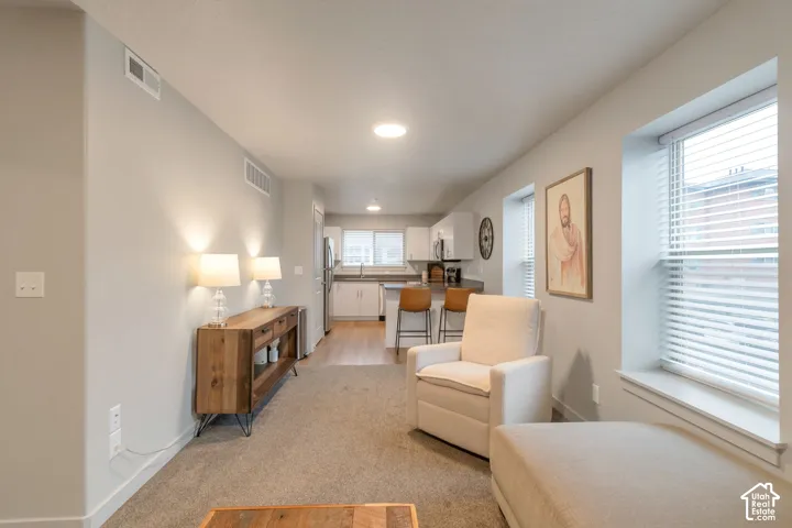 Light gray walls with recessed lighting, wood-finish flooring in kitchen, kitchen features stainless steel appliances, white cabinetry, and light-toned countertops