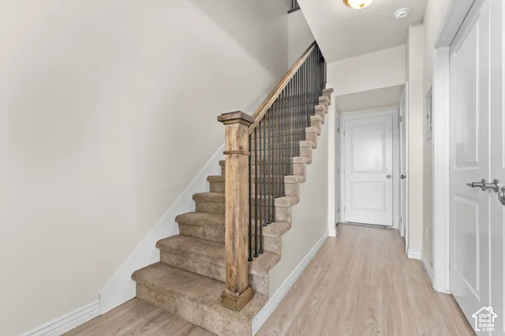 Carpeted staircase featuring a wood newel post and metal balusters