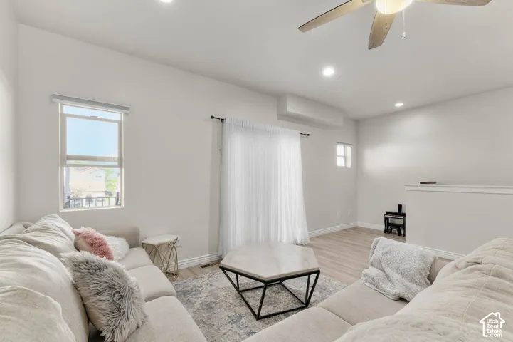 Recessed lighting, wood-finish flooring, ceiling fan, large window, and wall-mounted air conditioning unit