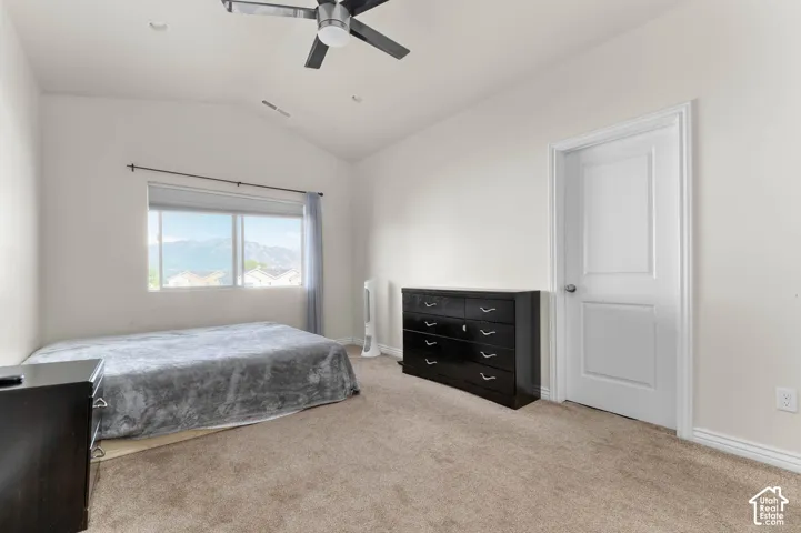 Vaulted ceiling, ceiling fan, carpeted flooring, large window, and white interior door