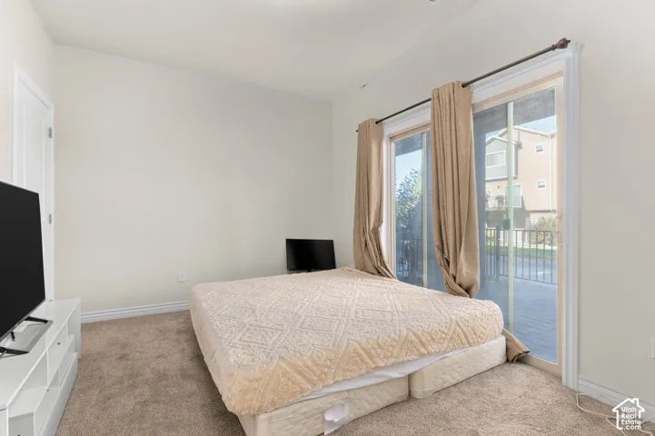 White interior door, light-colored carpeting, sliding glass patio door, exterior patio, and distant structures