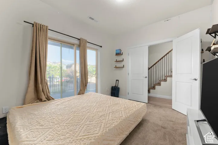Sliding glass door, wall-to-wall carpeting, double doors, interior staircase with dark wood-finish handrail and black metal spindles