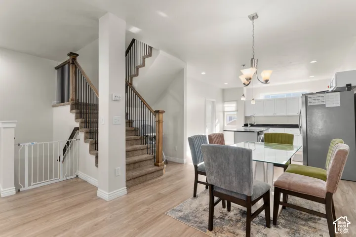 Open-concept living area with wood-finish flooring, a contemporary chandelier, and recessed lighting