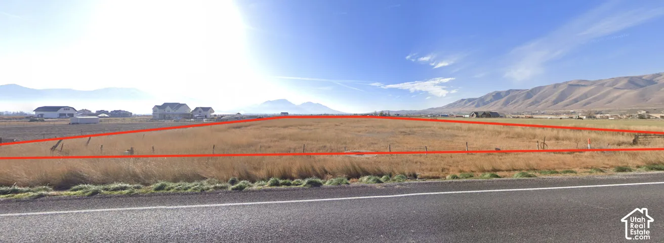 Expansive undeveloped land with a flat topography, bordered by a paved road