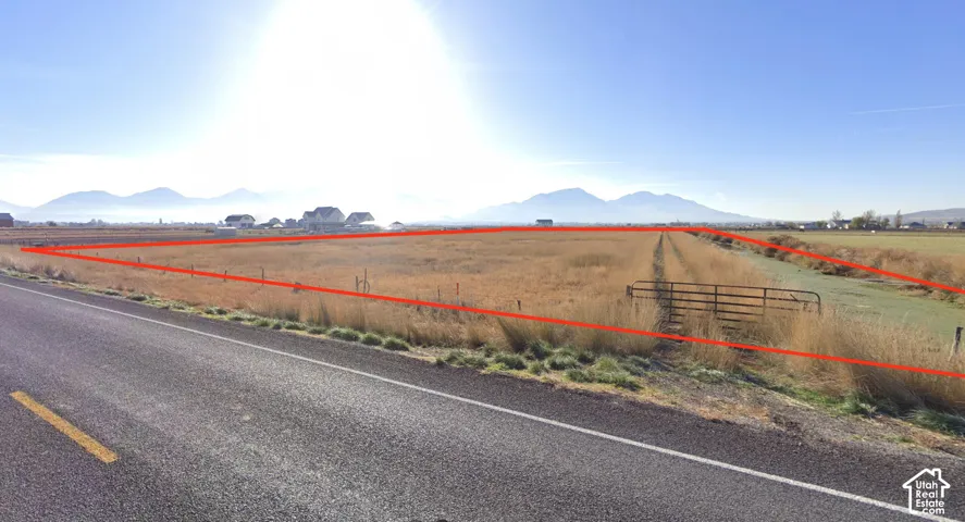 Expansive undeveloped land featuring a perimeter fence and a metal gate