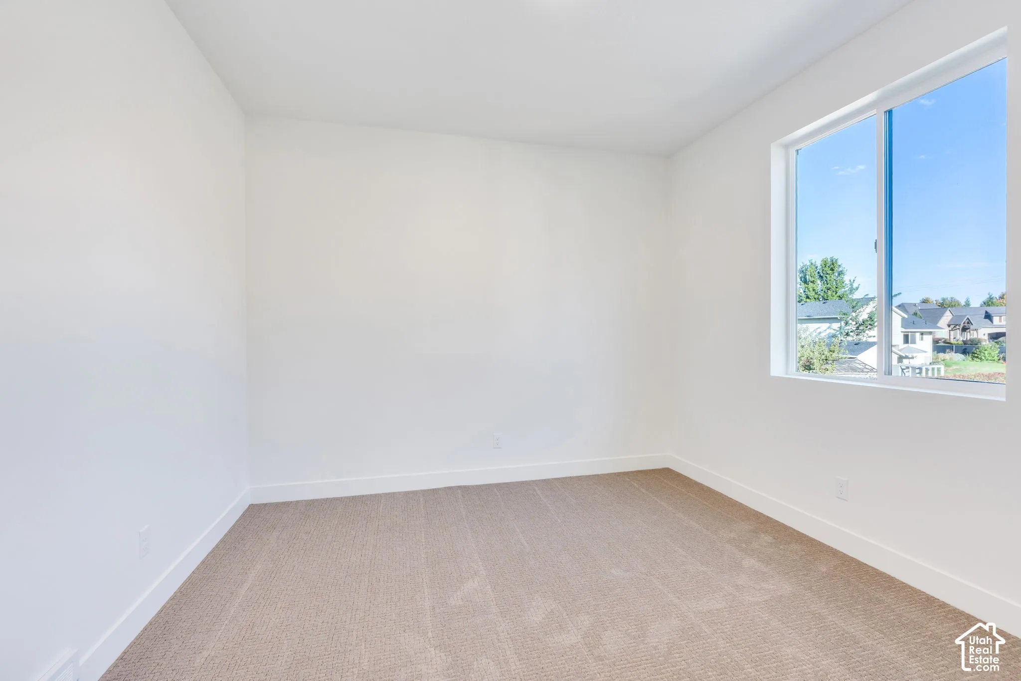 Neutral-toned carpeting with white wall paint and a large pane window