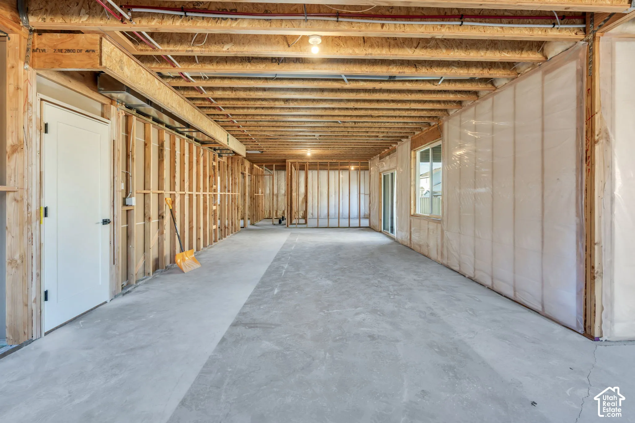 Unfinished basement featuring exposed wood framing, concrete flooring, and an egress window