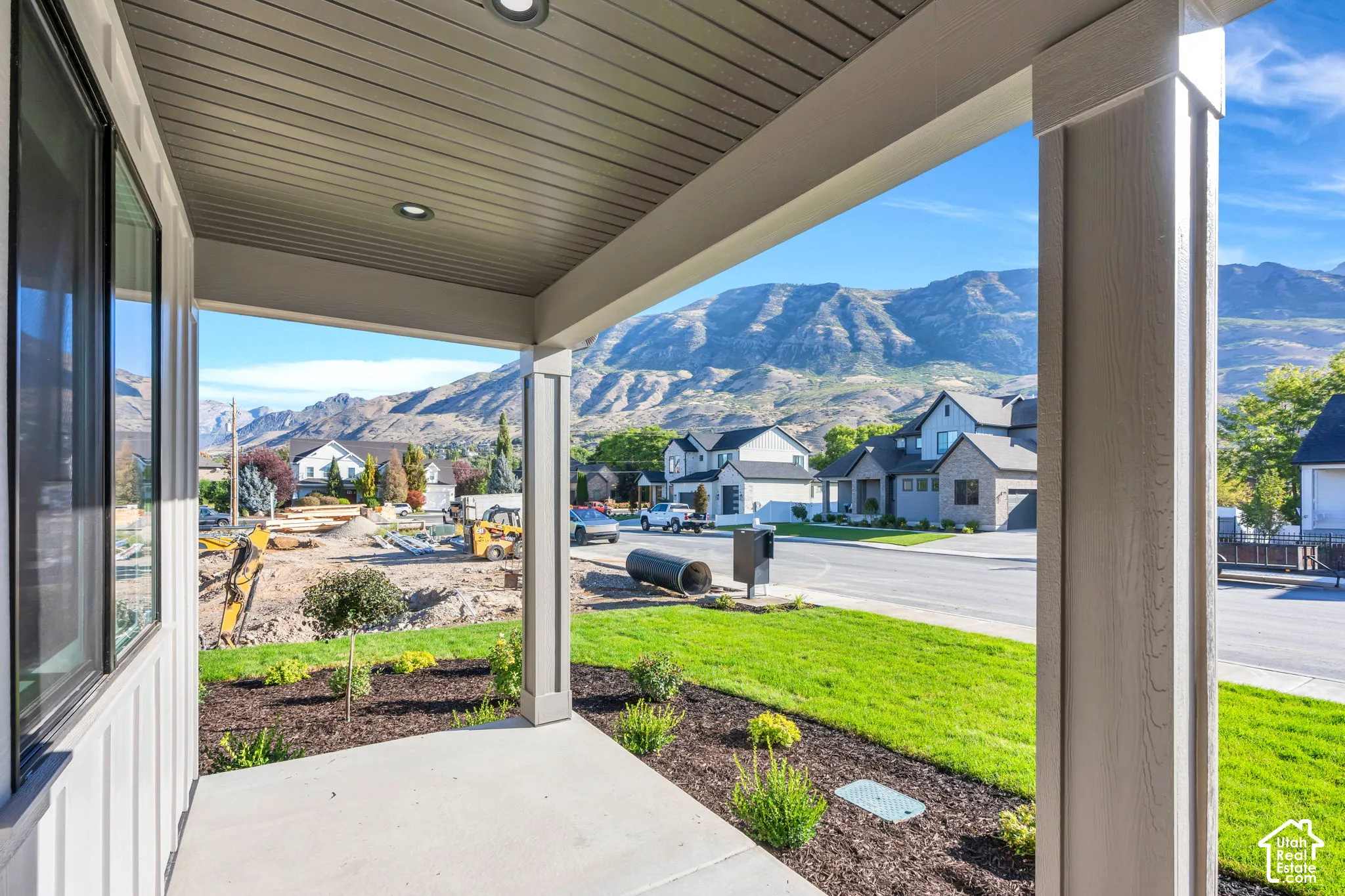 Covered front porch with recessed lighting, concrete flooring, and manicured landscaping