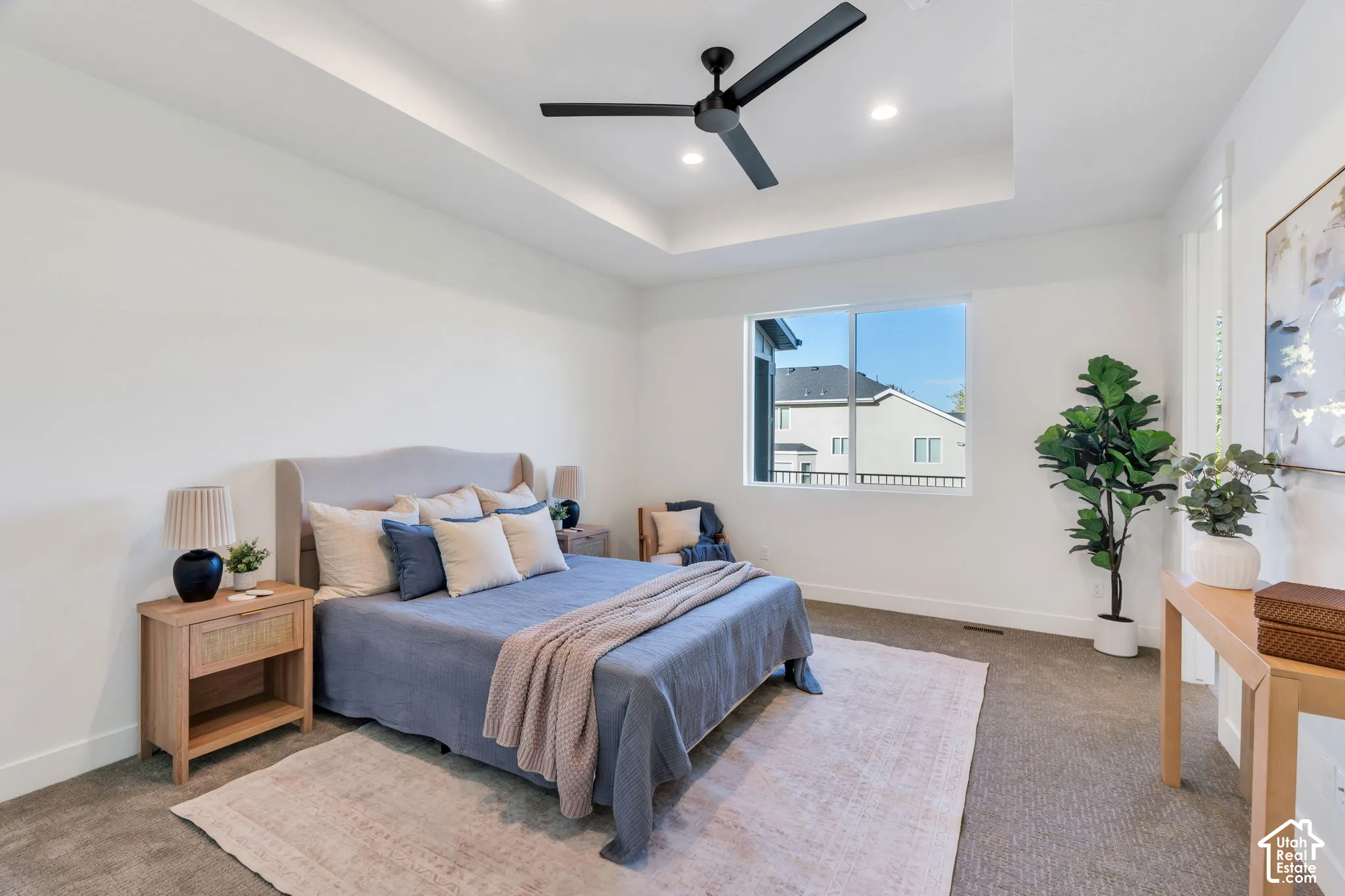 Tray ceiling with recessed lighting, ceiling fan, large window, and light-toned carpeting